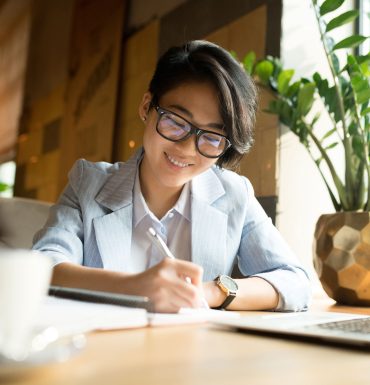 cheerful-asian-lady-filling-papers-in-cafe-R2FXU9G.jpg
